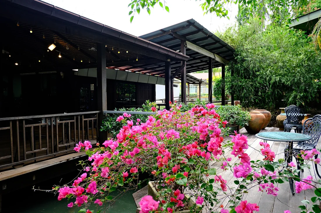 Lối đi đá bazan uốn lượn dẫn vào sảnh biệt thự giữa thảm cỏ và cây bụi